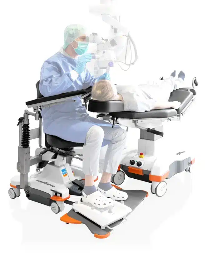 Cirujano en silla surgiForce operando con paciente en camilla eyeForce